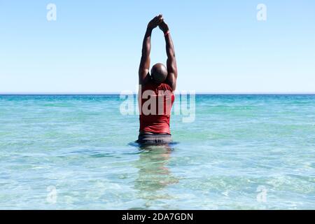 Hinten Porträt von fit jungen afrikanischen Mann im Meer stehen Und dabei Arme Stretching Workout Stockfoto