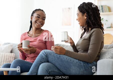 Zwei hübsche schwarze Damen trinken Tee zu Hause Stockfoto