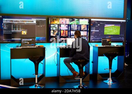 Mann mit Laptop und Fernsehbildschirmen Stockfoto