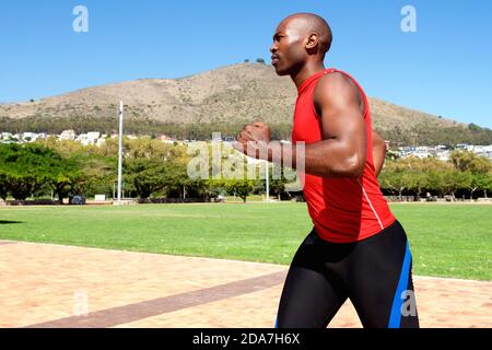 Seitenportrait von fit jungen afrikanischen Kerl läuft draußen an Der Park Stockfoto