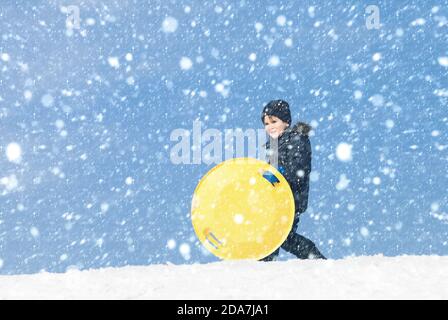 Lifestyle-Konzept. Junge spielt draußen an einem verschneiten Wintertag. Junge mit Schlitten. Rodeln im Winter Stockfoto