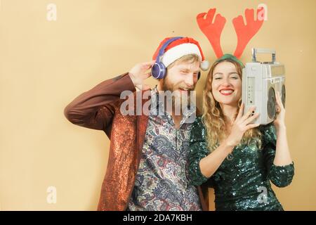 Fröhliches junges Paar feiert weihnachten Musik hören mit vintage boombox. Feiertags- und Partykonzept. Stockfoto