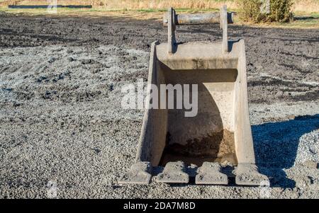 Eine leere freistehende schwere Bulldozer Eimer sitzen in der Schmutz auf einer Baustelle mit Kopierplatz Stockfoto