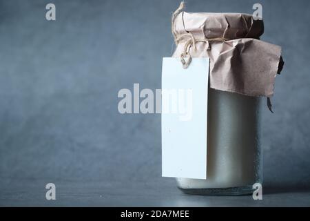 Kokosöl im Glas mit weißem Etikett auf schwarzem Hintergrund. Stockfoto