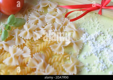 Zusammensetzung gesunder Lebensmittelzutaten auf gelbweißem Hintergrund, Draufsicht. Zutaten für macron, Spaghetti, Pasta. Tomaten, Basilikum, Parmes Stockfoto