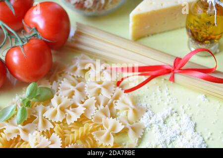 Zusammensetzung gesunder Lebensmittelzutaten auf gelbweißem Hintergrund, Draufsicht. Zutaten für macron, Spaghetti, Pasta. Tomaten, Basilikum, Parmes Stockfoto
