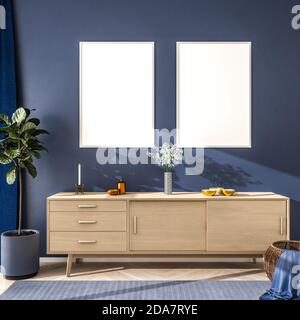 Interieur-Szene in blauer Farbstimmung: Holz-Sideboard mit Blumen, Schalen und eine Kerze auf der Oberseite. Zwei leere Bilderrahmen (70x100cm). Feigenbaum, Weidenbas Stockfoto