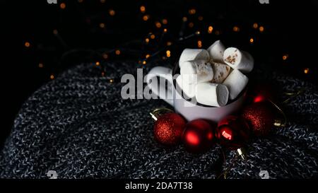 Tasse heiße Schokolade mit Marshmallow auf dunklem Hintergrund, Winter Weihnachten Heißgetränk mit roten weihnachtskugeln und Bokeh Lichter Stockfoto