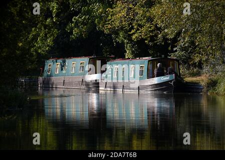 Zwei Narrow Boats spiegeln sich in den stillen Gewässern des Schönen Basingstoke Canal in der Nähe der Gerstenmähbrücke in Dogmersfield Stockfoto