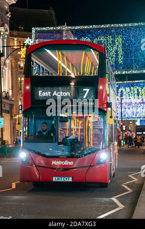 LONDON - 3. NOVEMBER 2020: Roter London Doppeldeckerbus mit Oxford Street beleuchtete Weihnachtsdekorationen im Hintergrund Stockfoto