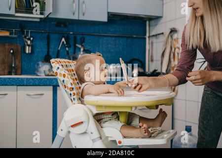 Babynahrung. Beste Finger Lebensmittel für Kleinkinder Babys. Kleinkind Baby Mädchen mit Knäckebrot, Müsli Cracker sitzen in Fütterungssessel. Stockfoto