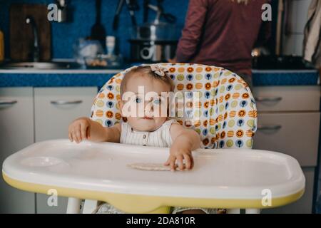 Babynahrung. Beste Finger Lebensmittel für Kleinkinder Babys. Kleinkind Baby Mädchen mit Knäckebrot, Müsli Cracker sitzen in Fütterungssessel. Stockfoto