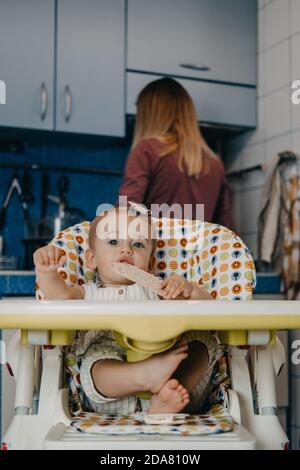 Babynahrung. Beste Finger Lebensmittel für Kleinkinder Babys. Kleinkind Baby Mädchen mit Knäckebrot, Müsli Cracker sitzen in Fütterungssessel. Stockfoto