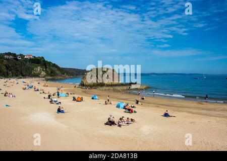 Menschen genießen die Sonne im Spätsommer an einem Sandstrand in der malerischen Küstenstadt Tenby, Wales Stockfoto