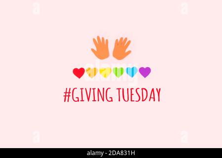 Konzept „Giving tuesday“ Minimal flach lag mit Text geben Dienstag Papierpalmen und Regenbogen Herzen auf pastellfarbenem Hintergrund. Stockfoto