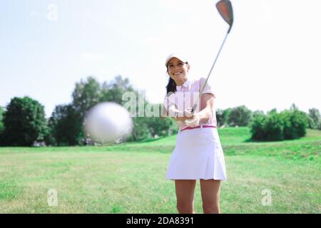 Frau Golfer macht einen Hit mit einem Verein auf Ball. Stockfoto