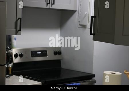 Moderne graue Küche verfügt über dunkelgraue flache Frontschränke gepaart mit weißen Quarz-Arbeitsplatten und einem glänzenden grauen linearen Fliesen backsplash. Nordwest Stockfoto