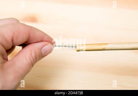 Nahaufnahme der Person, die mit Trinkhalm Reiniger Bürste wiederverwendbare Bambus Trinkhalm zu reinigen. Stockfoto