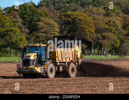 Nutzfahrzeug verteilt Gülle im Feld nach der Ernte, East Lothian, Schottland, Großbritannien Stockfoto