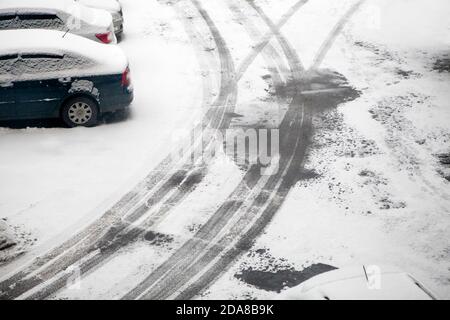 Erster Schnee. Spuren von vorbeifahrenden Autos auf dem Asphalt. Der Winter kommt Stockfoto