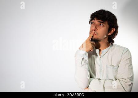 Junger hispanischer Mann in legerer Kleidung auf weißem Hintergrund Mit nachdenklichen und nachdenklichen Gesicht Stockfoto