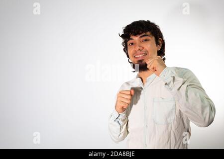 Junger hispanischer Mann in legerer Kleidung auf weißem Hintergrund Positive und gewinnende Haltung zeigen Stockfoto