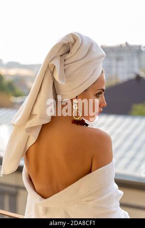 Wunderschönes Hotelmädchen in weißem Bademantel und Handtuch auf dem Balkon. Stockfoto