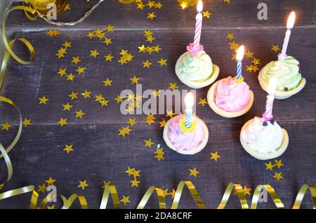Cupcake dekoriert mit bunten Geburtstagskerzen. Geschenke, goldene Serpentin, Sterne, feiern den Feiertag, Party Stockfoto
