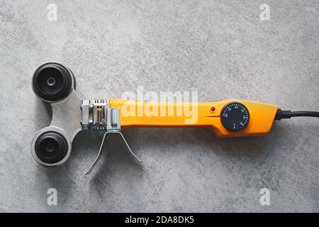 Gelber Lötkolben für PVC-Rohre auf grauem Hintergrund Stockfoto
