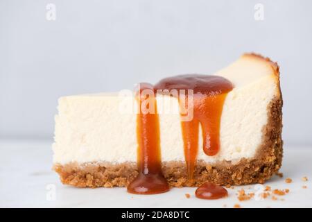 Käsekuchen mit gesalzener Karamellsauce auf grauem Hintergrund, Nahaufnahme. Perfekter Käsekuchen mit Karamell Stockfoto