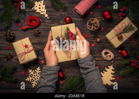 Weihnachtshintergrund mit Tannenbaum, Geschenkbox und Dekorationen am Holztisch. Stockfoto