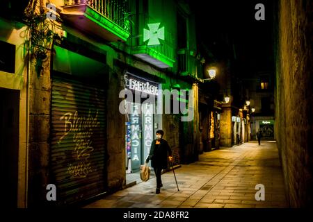 Barcelona, Spanien. 10. November 2020, Barcelona, Katalonien, Spanien: In der Altstadt von Barcelona kommt eine Frau mit Gesichtsmaske an einer Apotheke vorbei. Der spanische Gesundheitsminister erwartet, dass er bald einen Vertrag mit dem Pfizer-Drugmaker über 20 Millionen Dosen unterzeichnen wird und hofft, bis Anfang 2021 einen Coronavirus-Impfstoff für 10 Millionen Menschen erhalten zu können.Quelle: Jordi Boixareu/Alamy Live News Stockfoto