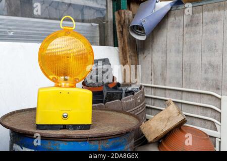 Gelbe Baulampe, die auf einem Ölfass auf einem Schrottplatz steht. Symbol der Konstruktion in einer chaotischen Situation, verwenden Sie als Website nicht gefunden Bild. Stockfoto