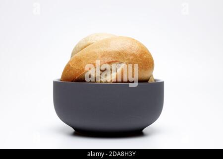 Zwei typisch deutsche Weizenbrötchen in einer dunkelgrauen Keramikschale auf weißem Uniformhintergrund werden goldgebackene Brötchen typisch in deutschland gebacken Stockfoto