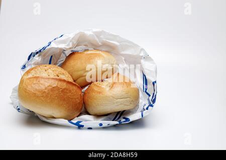 Drei Weizenbrötchen in einer blau-weißen Papiertüte auf uniformierten weißen Hintergrund, Made in Germany, typisch deutsches Frühstück Stockfoto