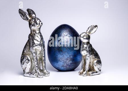 Zwei realistische Figuren eines osterhasen und eines königsblauen ostereiers, kreative ostern und Frühlingsdekoration 2020, Trendfarben auf weißem isoliertem Rücken Stockfoto