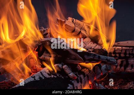Nahaufnahme von wild tanzenden Flammen, die Holz verbrennen, zeigt gelbes Licht und glühenden Esche Stockfoto