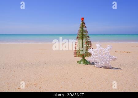 Weihnachtsschmuck, Kugeln und weihnachtsbaum in der Nähe des Meeres an einem hellen und sonnigen Tag. Neujahrskonzept.Schneeflocke auf dem Sand. Winterurlaub im Stockfoto