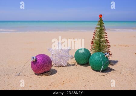 Weihnachtsschmuck, Kugeln und weihnachtsbaum in der Nähe des Meeres an einem hellen und sonnigen Tag. Neujahrskonzept.Schneeflocke auf dem Sand. Winterurlaub im Stockfoto