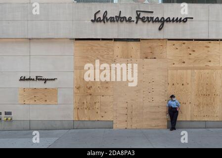 Ein Wachmann mit einer Maske steht vor einem geschlossenen Salvatore Ferragamo-Geschäft in der fünften Straße in Midtown. Stockfoto