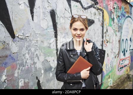 Frau in Lederjacke in der Nähe Graffiti an der Wand in Die Straße Stockfoto