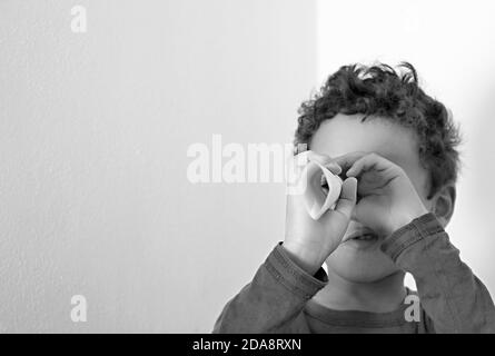 Junge Blick durch Fernglas Papierrolle auf weißem Hintergrund Stock Foto Stockfoto