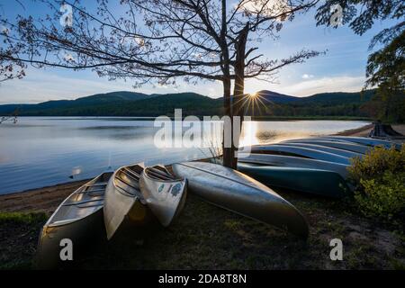 Blick bei Sonnenaufgang über den staatlichen Campingplatz Lewey Lake mit Kanus im Vordergrund. Adirondacks, New York Stockfoto