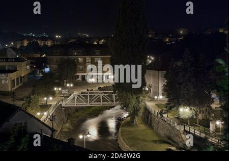 Alte Innenstadt von Knjazevac Stadt im Osten Serbiens. Metallbrücke am Timok Fluss, kleiner Park mit Promenade. Nachtaufnahmen, Langzeitbelichtung. Stockfoto