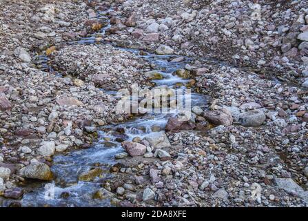 Buntes Bild eines kleinen Flusses, Wasser fließt zwischen den Steinen in italienischen Alpen. Stockfoto