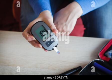 Frau, die den Glukosespiegel in ihrem Blut überprüft, gutes Ergebnis der Messung mit Glucometer Stockfoto