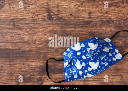 Handgemachte Stoffmasken auf Holzhintergrund, feiern Chanukka mit jüdischen Symbolen auf einer blauen Maske Stockfoto