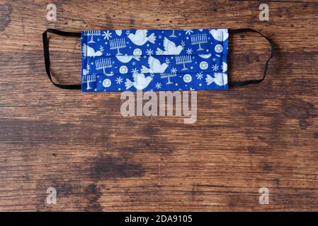 Handgemachte Stoffmasken auf Holzhintergrund, feiern Chanukka mit jüdischen Symbolen auf einer blauen Maske Stockfoto
