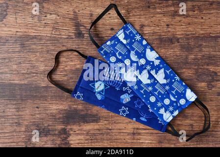 Handgemachte Stoffmasken auf Holzhintergrund, feiern Chanukka mit jüdischen Symbolen auf einer blauen Maske Stockfoto