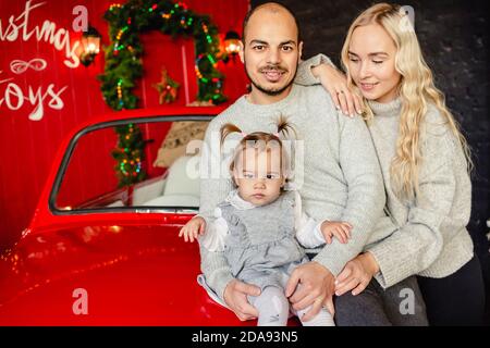 Nette junge Familie - Papa, Mama und Baby Mädchen mit Weihnachten Hintergrund hinter. Speicherplatz kopieren. Familie, Kindheit, Urlaub und Menschen Konzept. Stockfoto